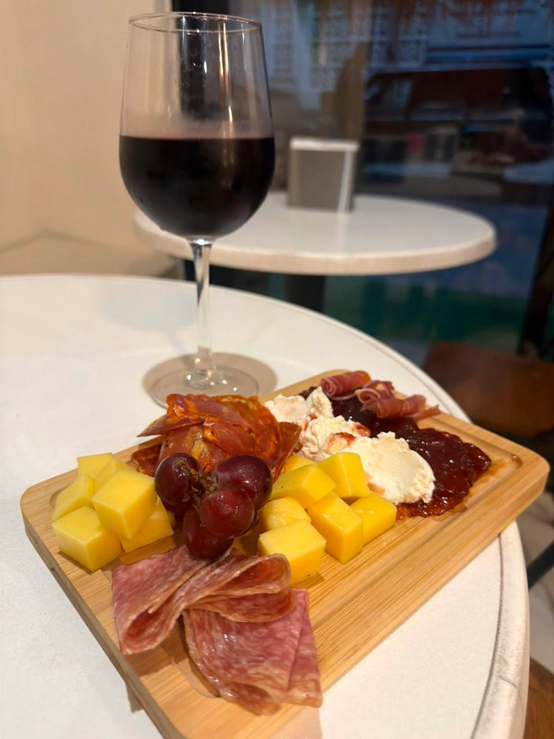 Tabla de carnes frías y quesos con copa de vino tinto