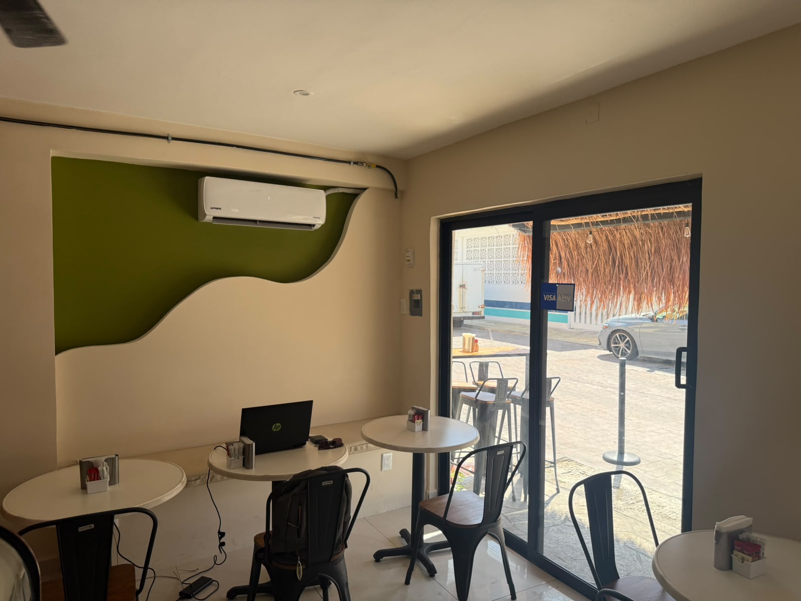 Interior de Marea con pared verde olivo y mesas redondas